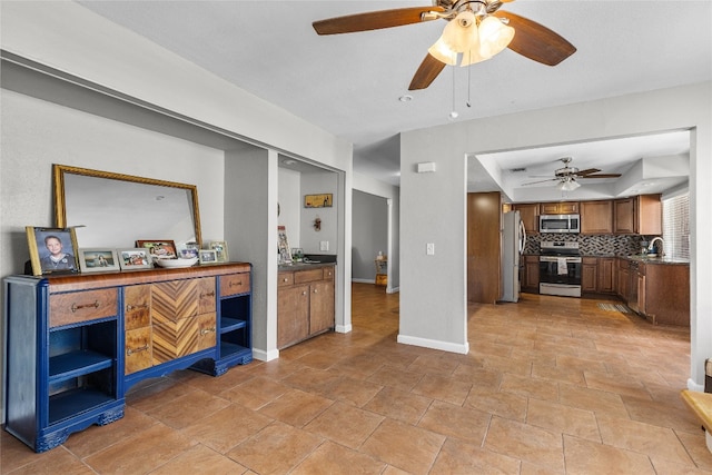 interior space featuring ceiling fan, sink, backsplash, and appliances with stainless steel finishes