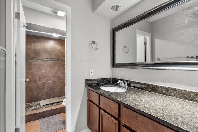 bathroom with toilet, vanity, and tiled shower