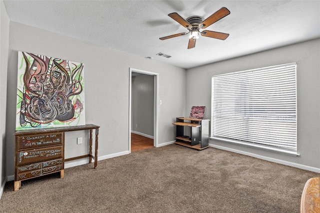 misc room with carpet flooring, ceiling fan, and a textured ceiling