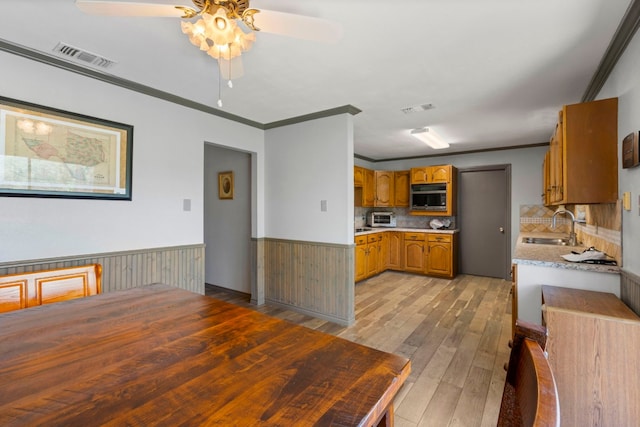 kitchen with backsplash, ceiling fan, hardwood / wood-style floors, stainless steel microwave, and sink