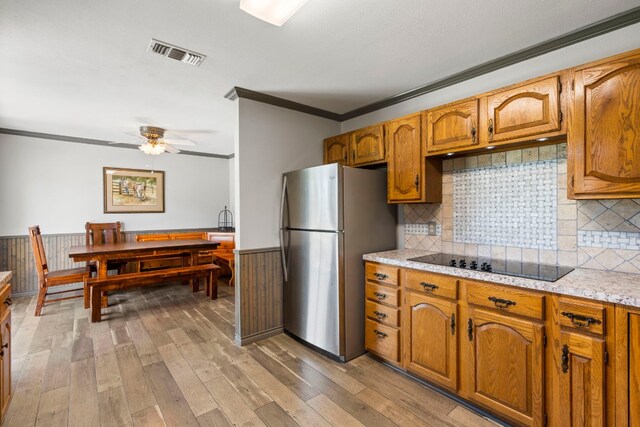 kitchen featuring black electric cooktop, stainless steel fridge, light hardwood / wood-style flooring, and tasteful backsplash