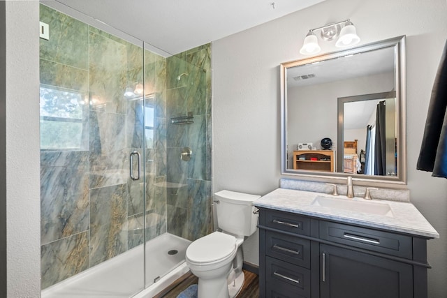 bathroom featuring a shower with shower door, vanity with extensive cabinet space, and toilet