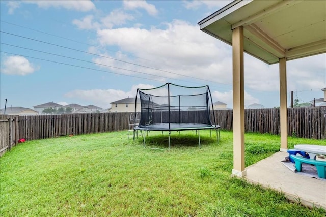 view of yard with a trampoline and a patio