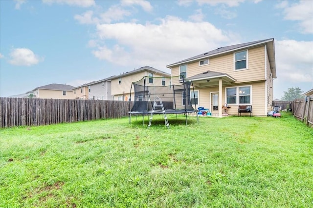 back of house with a trampoline and a lawn