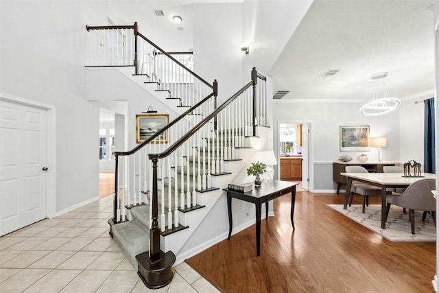 staircase featuring a chandelier, wood-type flooring, and ornamental molding