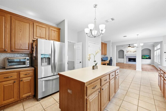 kitchen featuring light tile patterned floors, stainless steel fridge, pendant lighting, decorative backsplash, and a kitchen island