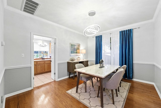 dining space with a notable chandelier, light wood-type flooring, and crown molding