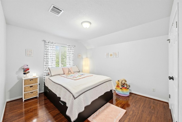 bedroom with a textured ceiling, dark wood-type flooring, and vaulted ceiling