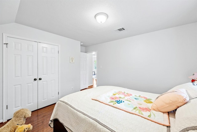 bedroom with hardwood / wood-style flooring, vaulted ceiling, and a closet