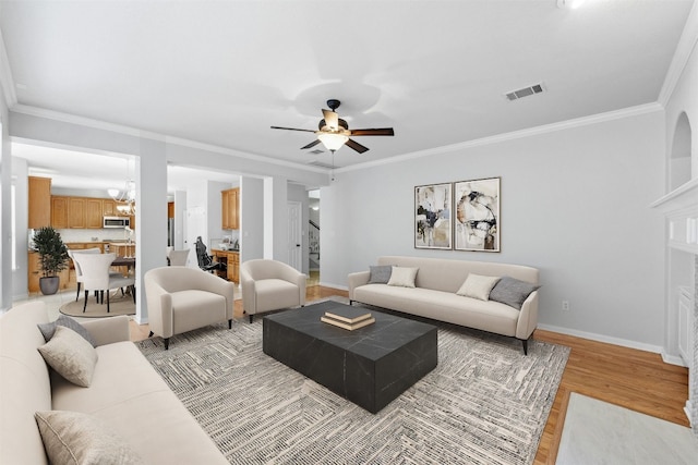 living room featuring ceiling fan, light hardwood / wood-style floors, and crown molding