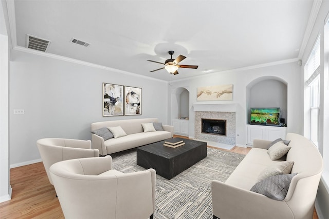 living room with light hardwood / wood-style floors, ceiling fan, and ornamental molding