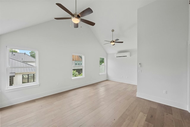 unfurnished living room with high vaulted ceiling, light hardwood / wood-style flooring, a wall unit AC, and a healthy amount of sunlight