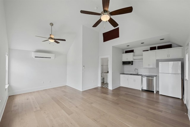 unfurnished living room with a wall mounted air conditioner, light hardwood / wood-style floors, high vaulted ceiling, and sink