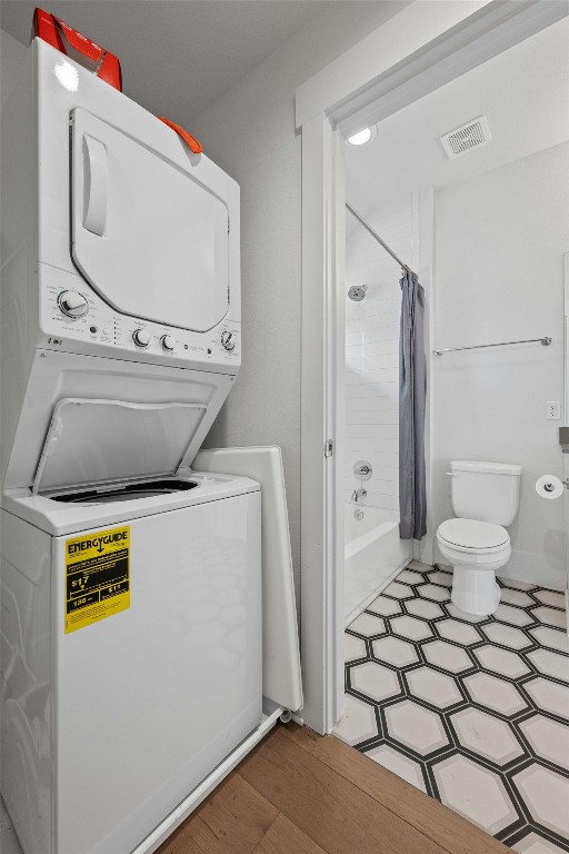 laundry room with stacked washer and dryer and hardwood / wood-style floors