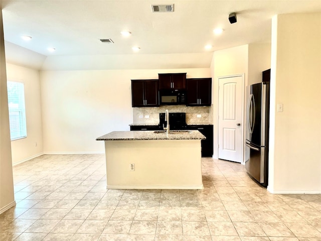 kitchen featuring stainless steel fridge, tasteful backsplash, an island with sink, light tile flooring, and stove