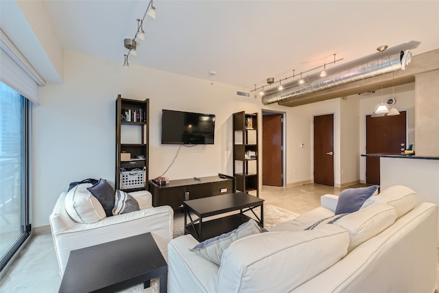 living room with baseboards, visible vents, and track lighting