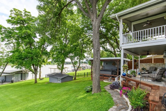 view of yard featuring ceiling fan, a balcony, an outbuilding, and a hot tub