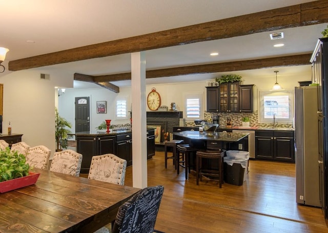 dining area with beamed ceiling, sink, and dark wood-type flooring