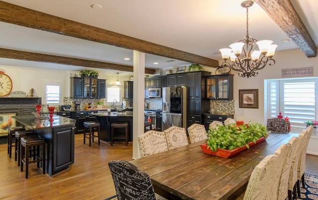 dining area featuring beam ceiling, dark hardwood / wood-style floors, a wealth of natural light, and a notable chandelier