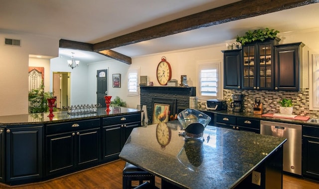 kitchen with stainless steel dishwasher, dark hardwood / wood-style floors, dark stone counters, a kitchen island, and ornamental molding