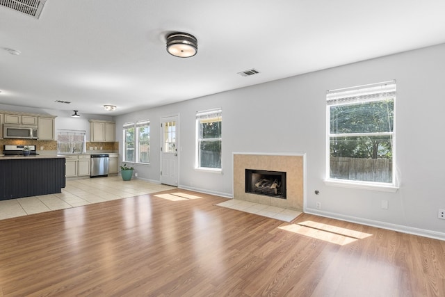 unfurnished living room featuring a tile fireplace and light wood-type flooring