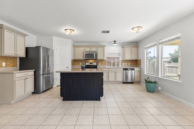 kitchen with backsplash, light tile patterned floors, cream cabinetry, and appliances with stainless steel finishes