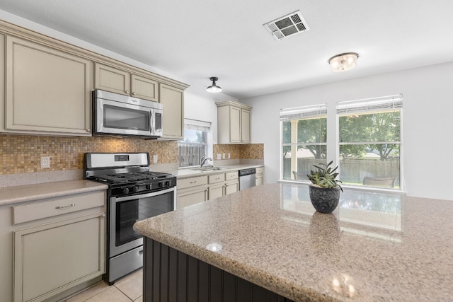 kitchen with cream cabinets, backsplash, stainless steel appliances, and sink