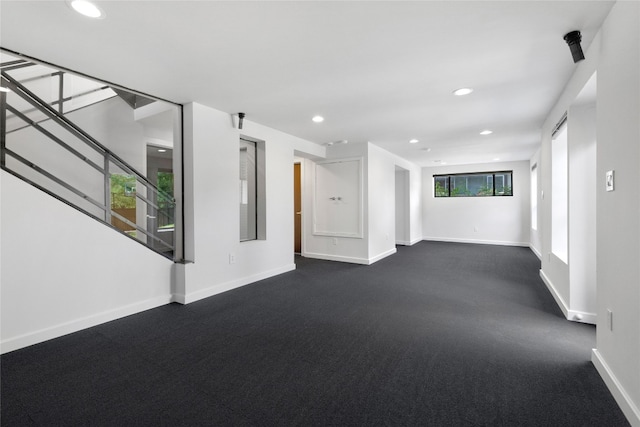 unfurnished living room with dark colored carpet and a wealth of natural light