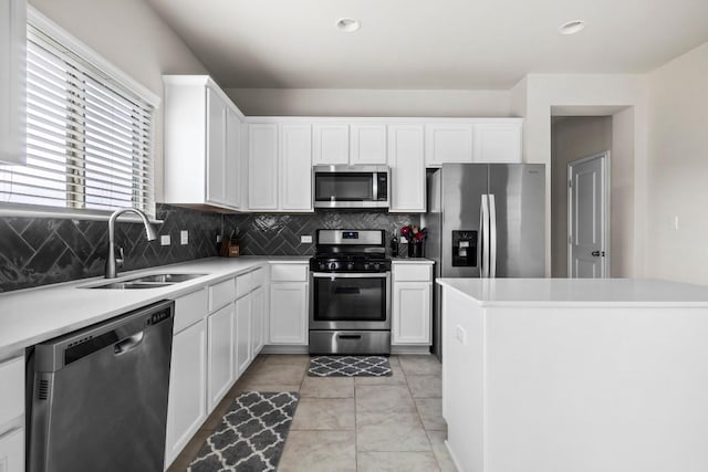 kitchen featuring sink, light tile patterned floors, decorative backsplash, white cabinets, and appliances with stainless steel finishes