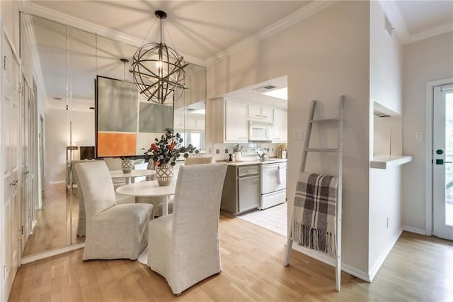 dining room with a wealth of natural light, light hardwood / wood-style flooring, ornamental molding, and a notable chandelier