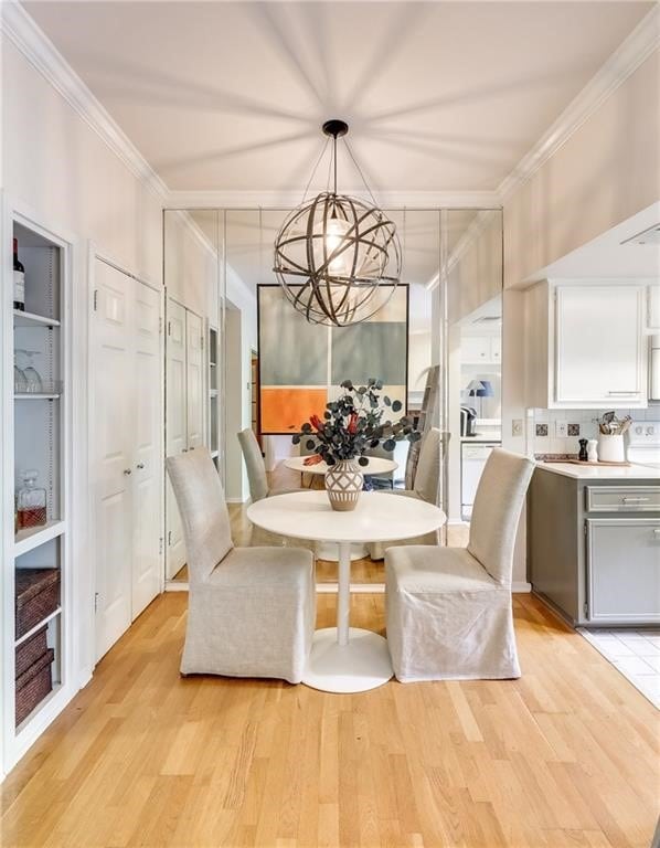 dining space with light hardwood / wood-style flooring, crown molding, and a notable chandelier