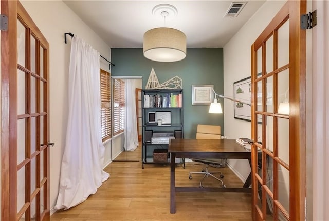 home office with french doors and light hardwood / wood-style flooring