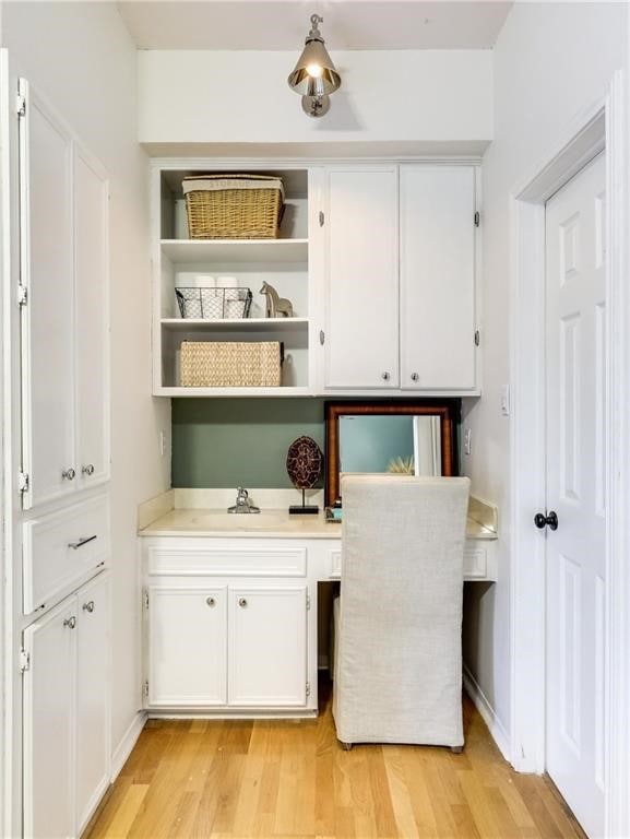 bar featuring white cabinets, light hardwood / wood-style floors, and sink