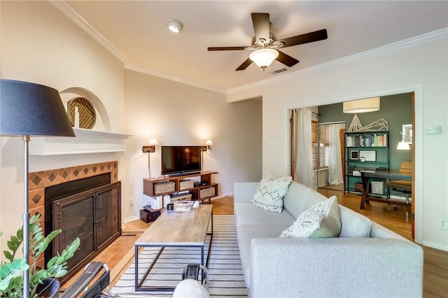 living room featuring a fireplace, hardwood / wood-style floors, ceiling fan, and ornamental molding