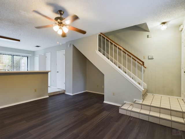 unfurnished living room featuring ceiling fan, dark wood-type flooring, and a textured ceiling