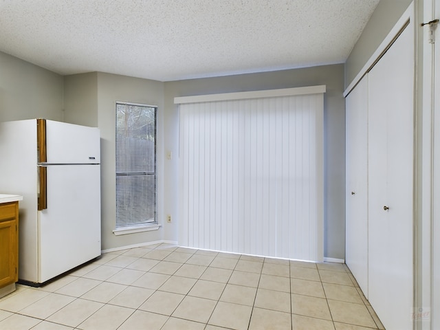 kitchen featuring light tile patterned floors, a textured ceiling, and white fridge