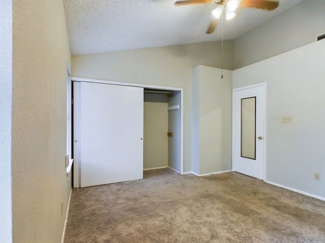 unfurnished bedroom with a closet, carpet, ceiling fan, high vaulted ceiling, and a textured ceiling