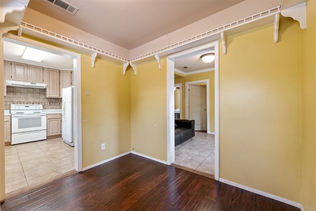 interior space with light hardwood / wood-style floors, crown molding, white appliances, backsplash, and light brown cabinetry