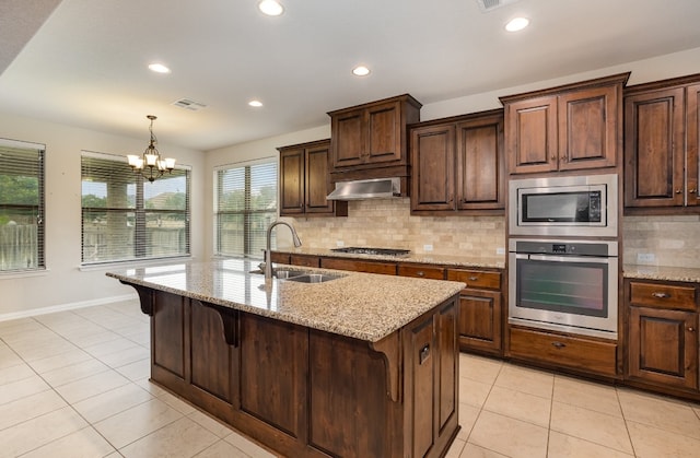 kitchen with a kitchen island with sink, stainless steel appliances, sink, extractor fan, and a notable chandelier