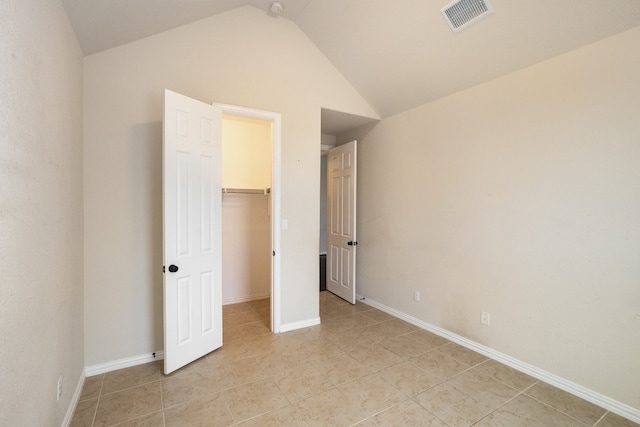 unfurnished bedroom with lofted ceiling, a spacious closet, a closet, and light tile patterned floors