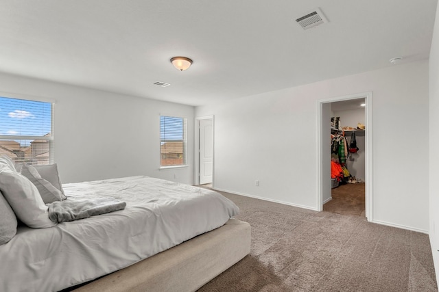 carpeted bedroom with a walk in closet and a closet