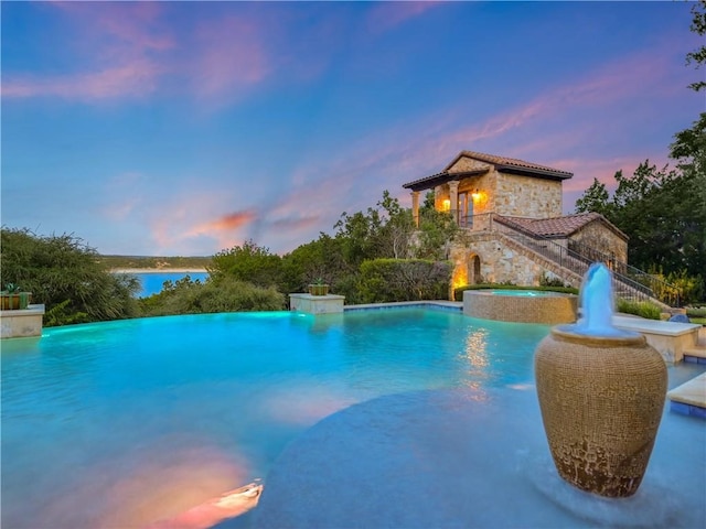 pool at dusk featuring pool water feature