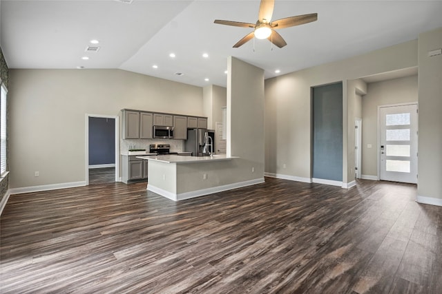 kitchen with ceiling fan, gray cabinets, stainless steel appliances, vaulted ceiling, and dark hardwood / wood-style flooring