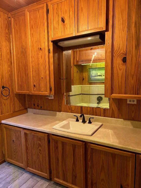 kitchen featuring light wood-type flooring, wooden walls, and sink