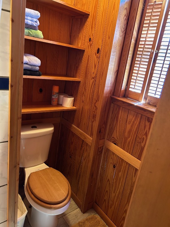 bathroom with wood walls and toilet