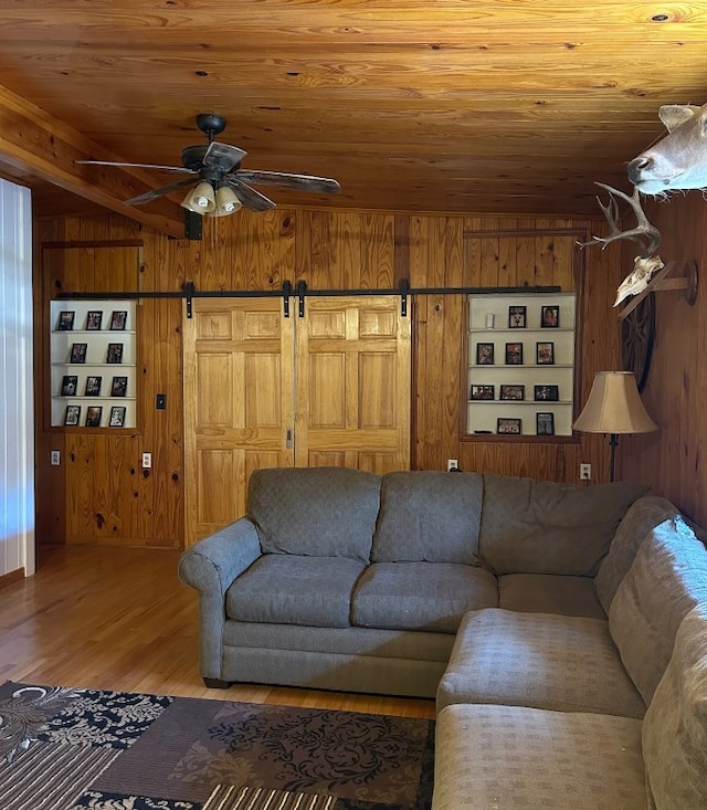 living room with wood ceiling, wooden walls, hardwood / wood-style flooring, and a barn door