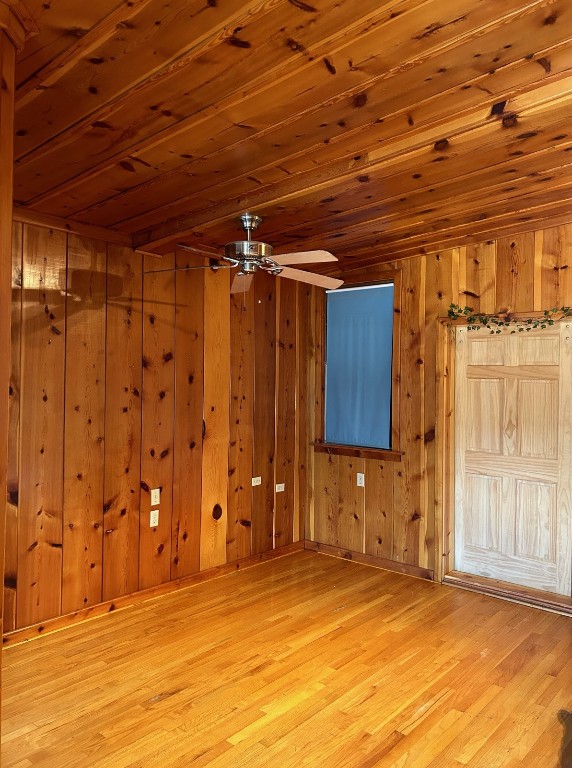 unfurnished room featuring wood walls, ceiling fan, light wood-type flooring, and wood ceiling