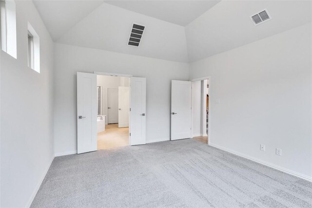 unfurnished bedroom with light carpet and high vaulted ceiling