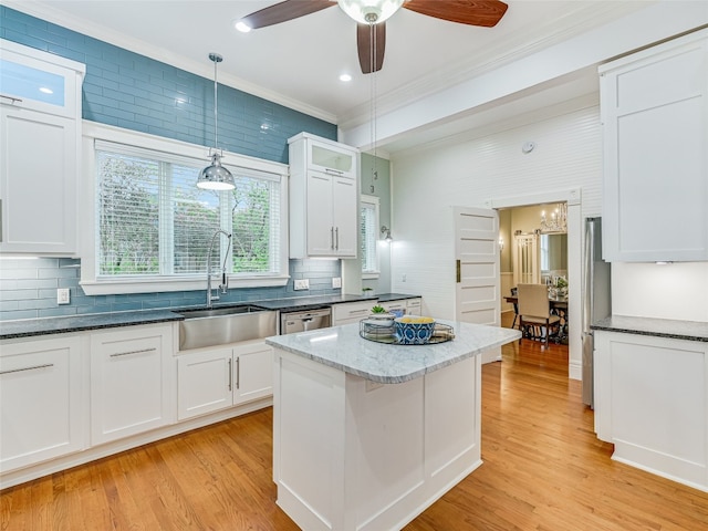 kitchen with light wood-type flooring, glass insert cabinets, ornamental molding, and white cabinets