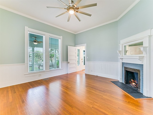 unfurnished living room with a brick fireplace, ceiling fan, hardwood / wood-style flooring, and crown molding